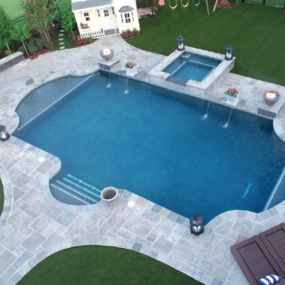 A luxurious pool deck designed with natural stone pavers, offering a timeless and elegant area for lounging and enjoying the aquatic surroundings.