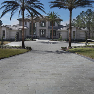 A beautifully designed driveway made of natural stone pavers, showcasing a seamless blend of elegance and durability.