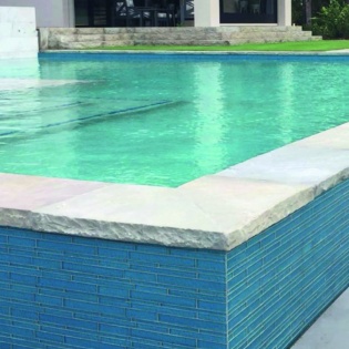 An exquisite pool deck featuring chiseled natural stone coping, creating a classic and sophisticated area for relaxation and enjoyment by the water.